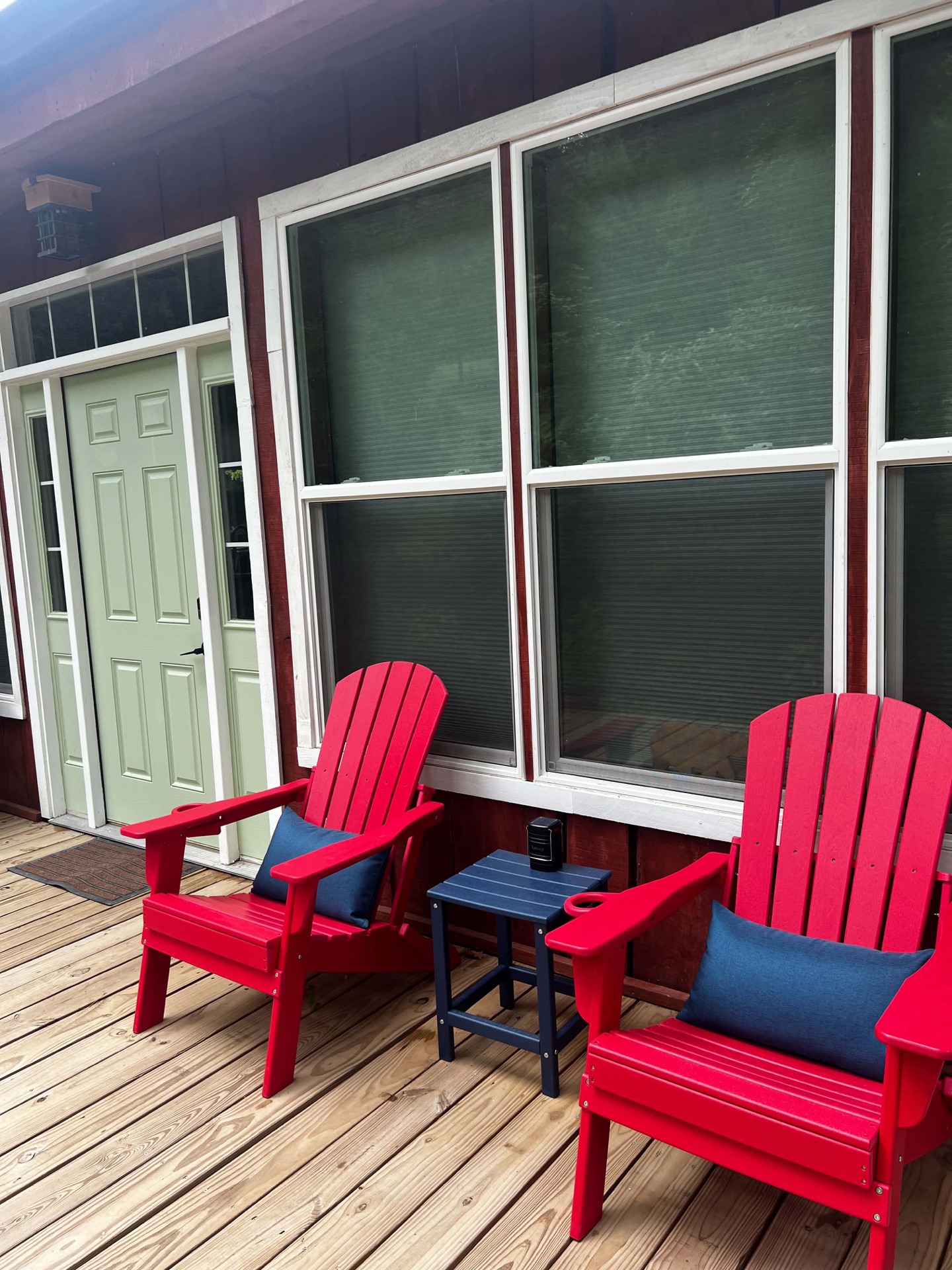 Front porch of the Hideout barndominium studio with red Adirondack chairs by the sage-green door